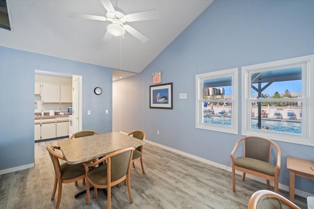 dining area with ceiling fan, high vaulted ceiling, and light hardwood / wood-style flooring