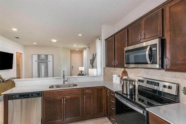 kitchen with appliances with stainless steel finishes, backsplash, kitchen peninsula, and sink