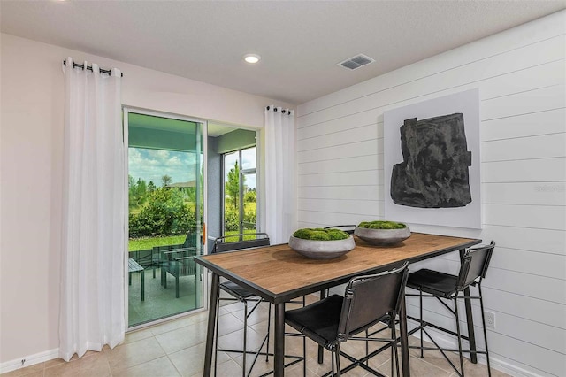 dining area with light tile patterned floors and wood walls