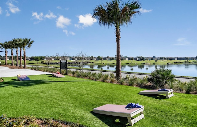 view of property's community with a water view and a lawn