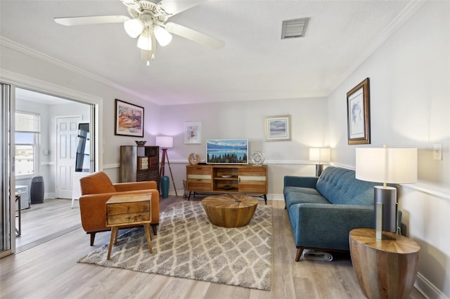 living room with ceiling fan, ornamental molding, and light wood-type flooring