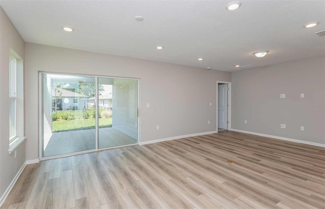 empty room with light wood-type flooring and a textured ceiling