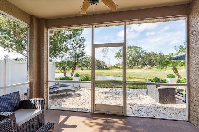 sunroom / solarium featuring a water view, plenty of natural light, and ceiling fan