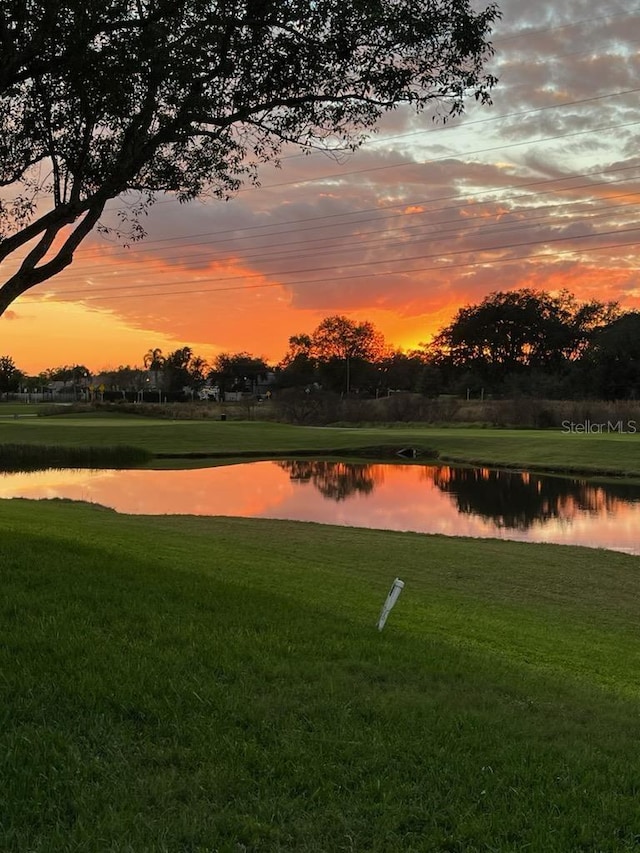 surrounding community with a water view and a lawn