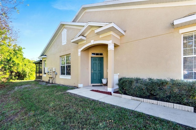 view of exterior entry featuring a lawn