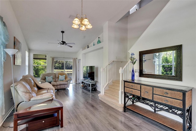 living room with ceiling fan with notable chandelier, light wood-type flooring, and high vaulted ceiling