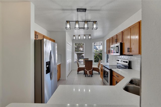 kitchen featuring hanging light fixtures, stainless steel appliances, a textured ceiling, and sink