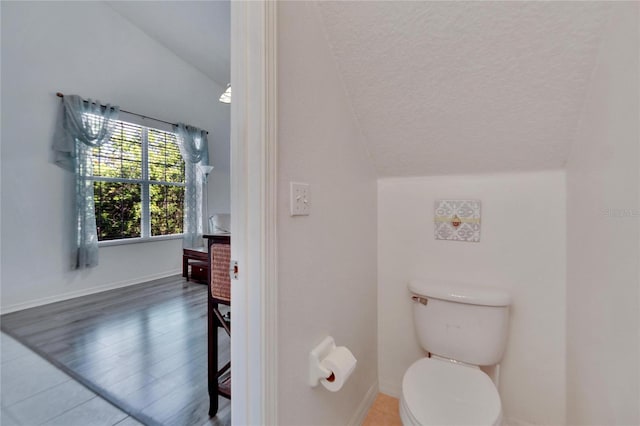 bathroom featuring a textured ceiling, hardwood / wood-style floors, vaulted ceiling, and toilet