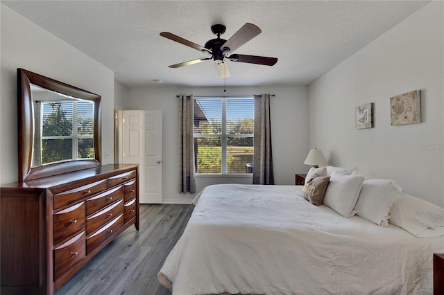 bedroom with ceiling fan, a textured ceiling, and light hardwood / wood-style flooring