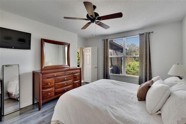 bedroom with ceiling fan, light hardwood / wood-style flooring, and a textured ceiling