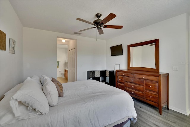 bedroom featuring connected bathroom, ceiling fan, light hardwood / wood-style floors, and a textured ceiling