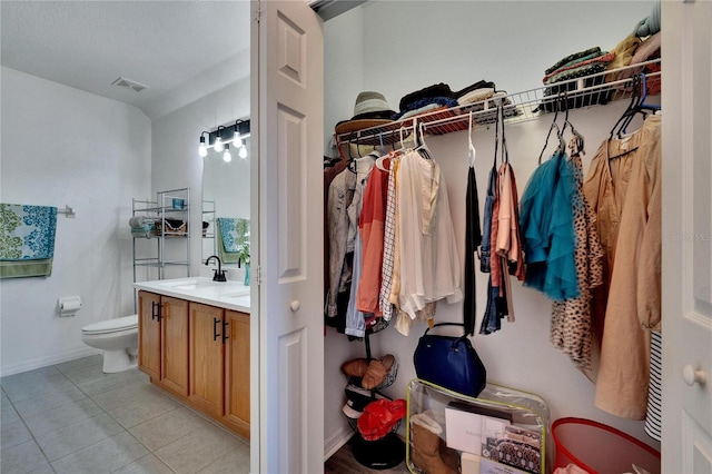 spacious closet featuring sink and light tile patterned floors