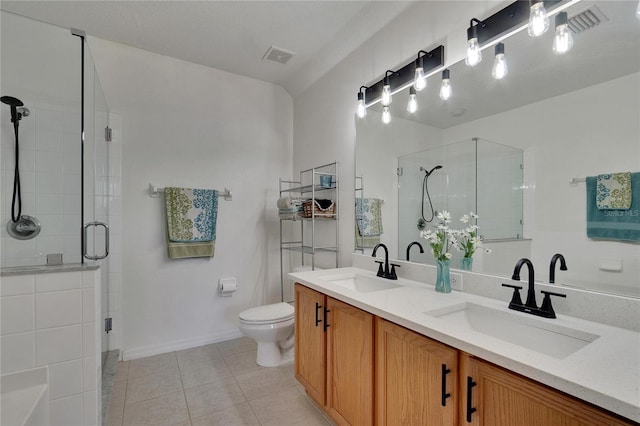 bathroom featuring tile patterned flooring, vanity, a shower with shower door, and toilet