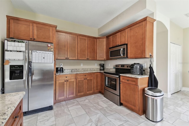 kitchen with stainless steel appliances and light stone counters