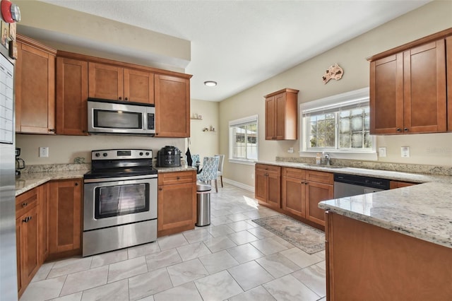 kitchen featuring light stone countertops, appliances with stainless steel finishes, light tile patterned floors, and sink