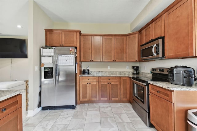 kitchen with light stone countertops and appliances with stainless steel finishes