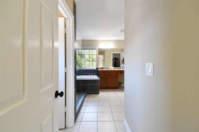 bathroom with tile patterned floors, a tub, vanity, and a textured ceiling