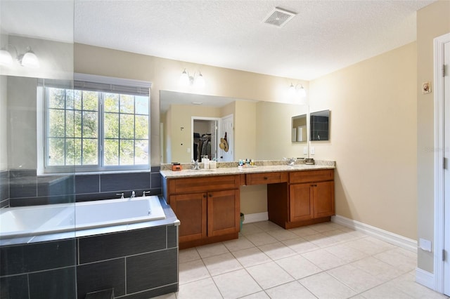 bathroom with tile patterned floors, tiled bath, vanity, and a textured ceiling