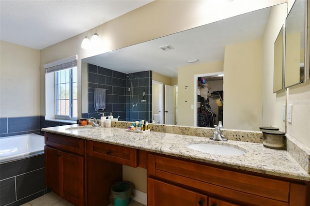 bathroom with tiled tub, tile patterned flooring, and vanity