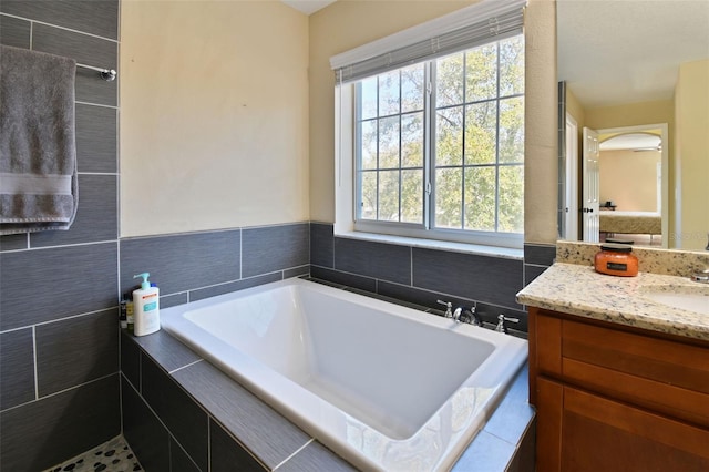 bathroom with vanity, a relaxing tiled tub, and tile walls