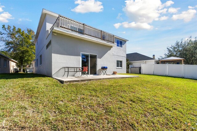 rear view of property featuring a yard, a patio area, and a balcony