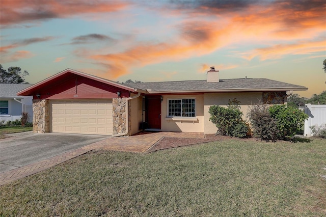 ranch-style home with a garage and a lawn