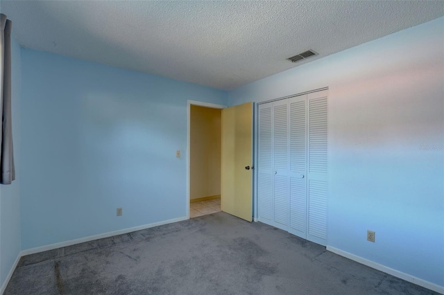 unfurnished bedroom with light carpet, a textured ceiling, and a closet