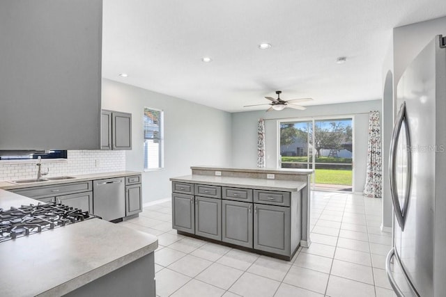 kitchen with gray cabinets, tasteful backsplash, sink, a center island, and stainless steel appliances