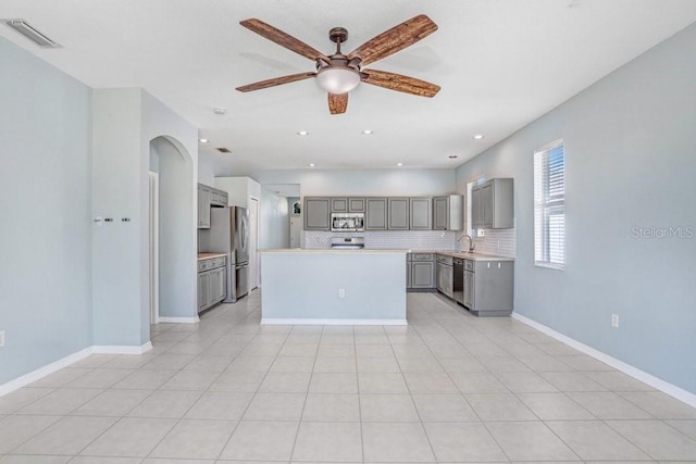 kitchen with light tile patterned flooring, appliances with stainless steel finishes, a center island, and gray cabinetry