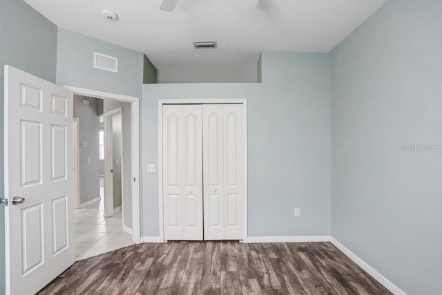 unfurnished bedroom featuring ceiling fan, wood-type flooring, and a closet