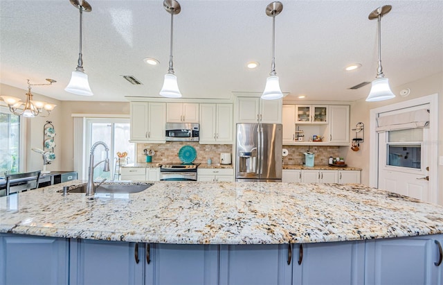 kitchen featuring appliances with stainless steel finishes, visible vents, a sink, and hanging light fixtures