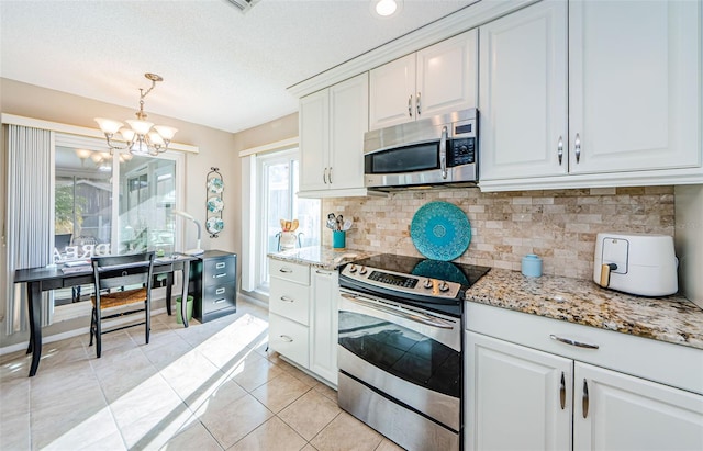 kitchen featuring light tile patterned floors, stainless steel appliances, hanging light fixtures, backsplash, and white cabinets