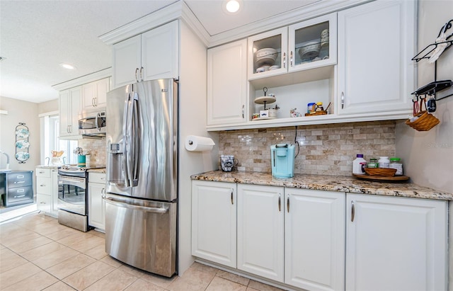 kitchen featuring light stone counters, stainless steel appliances, white cabinets, open shelves, and glass insert cabinets