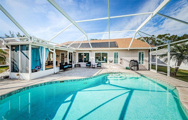 back of house featuring glass enclosure, an outdoor pool, and a patio