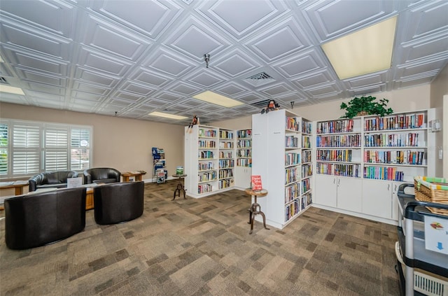 carpeted office space featuring an ornate ceiling and wall of books