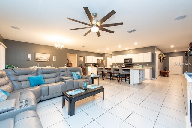 tiled living room featuring ceiling fan with notable chandelier