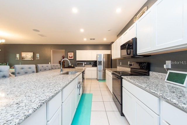 kitchen with black appliances, light stone counters, white cabinetry, and sink