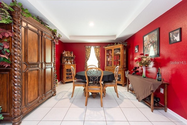 tiled dining space featuring a raised ceiling