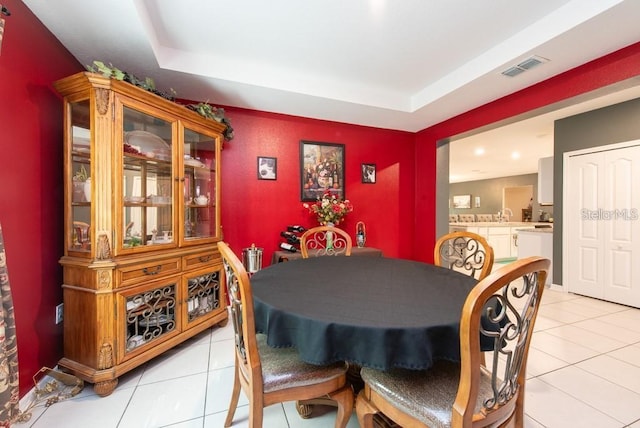 dining space featuring a raised ceiling, light tile patterned floors, and sink