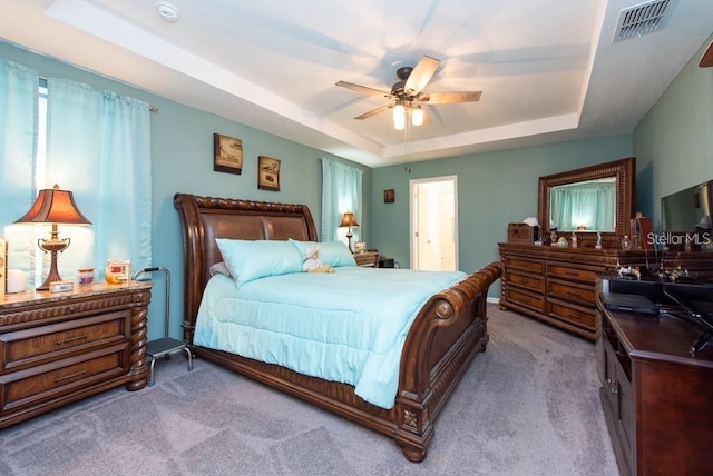 carpeted bedroom featuring a raised ceiling and ceiling fan