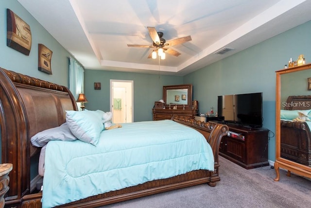 carpeted bedroom featuring a raised ceiling and ceiling fan