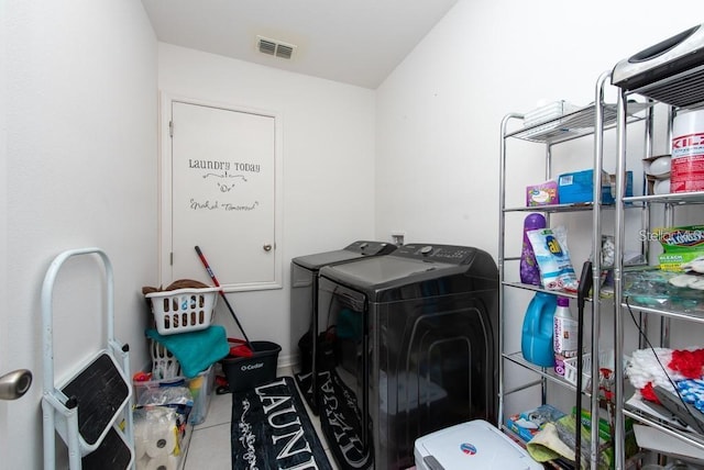 clothes washing area with washing machine and dryer and tile patterned floors