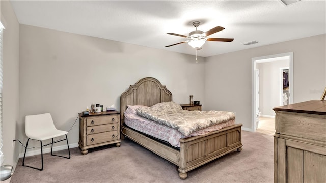 carpeted bedroom with ensuite bath and ceiling fan