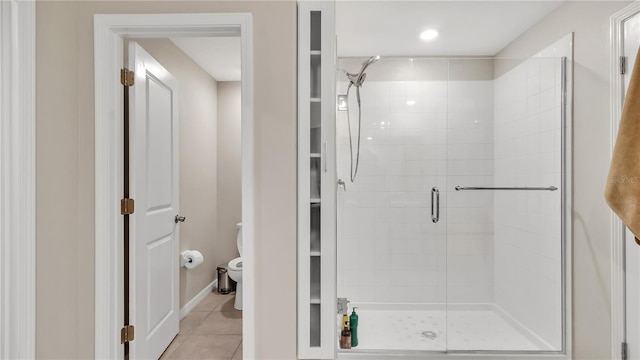 bathroom with tile patterned floors, toilet, and a shower with door