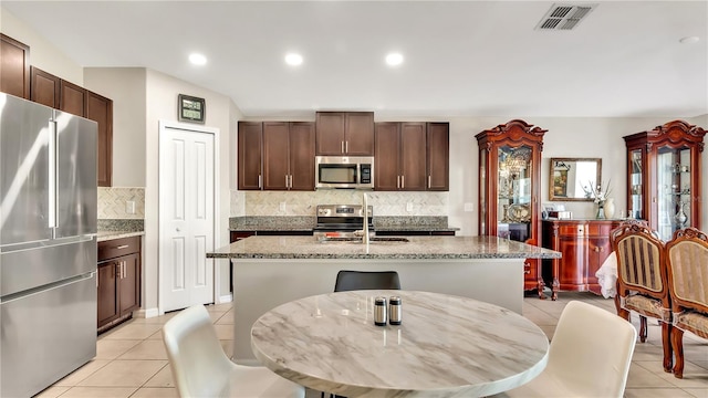 kitchen featuring sink, a center island with sink, light tile patterned flooring, and appliances with stainless steel finishes