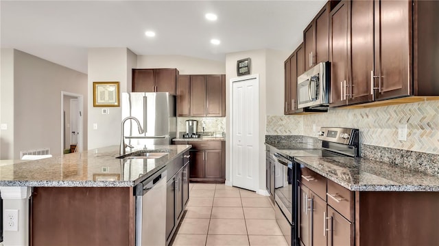 kitchen featuring a center island with sink, sink, light tile patterned floors, tasteful backsplash, and stainless steel appliances