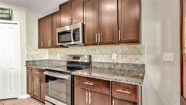 kitchen with light stone counters, backsplash, dark brown cabinets, light tile patterned floors, and appliances with stainless steel finishes