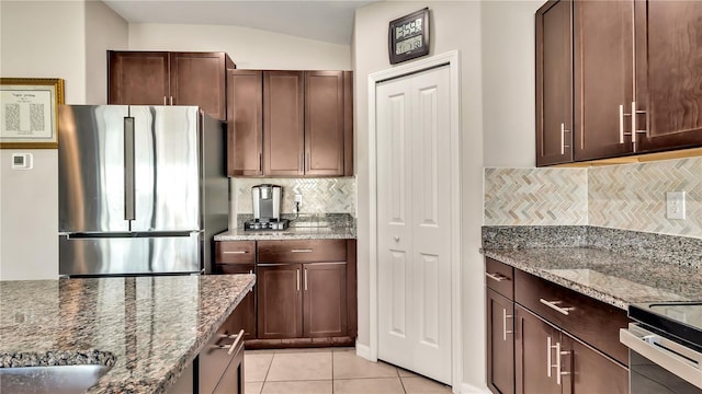 kitchen featuring light stone countertops, backsplash, stainless steel appliances, and vaulted ceiling