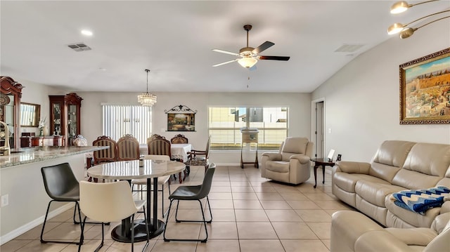 dining area with vaulted ceiling, light tile patterned floors, and ceiling fan with notable chandelier