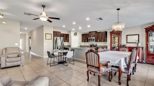 tiled dining space featuring lofted ceiling, sink, and ceiling fan with notable chandelier